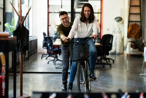 Colleagues in office. Businesswoman and businessman with bicycle. Two friends having fun together © JustLife