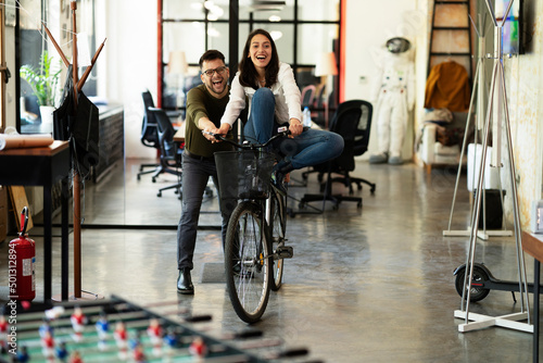 Colleagues in office. Businesswoman and businessman with bicycle. Two friends having fun together