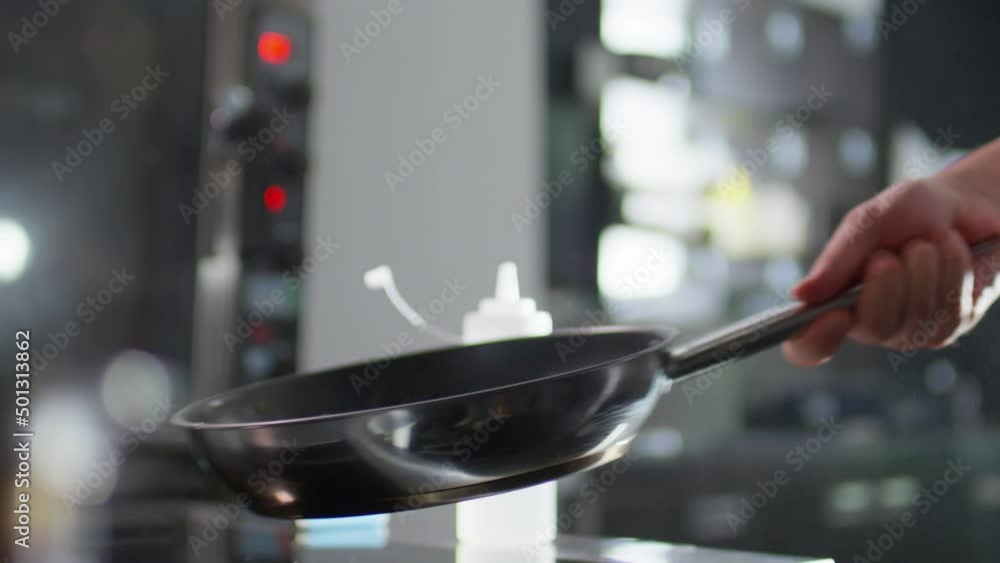 Slow motion close up shot of hand of male chef tossing vegetables on skillet while frying in restaurant kitchen Slow motion close up shot of hand of male chef tossing vegetables on skillet while frying in restaurant kitchen