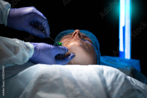 A doctor plastic surgeon removes a double chin from a female patient with the help of self-absorbing mesothreads. Modern plastic surgery, facelift. Close-up photo