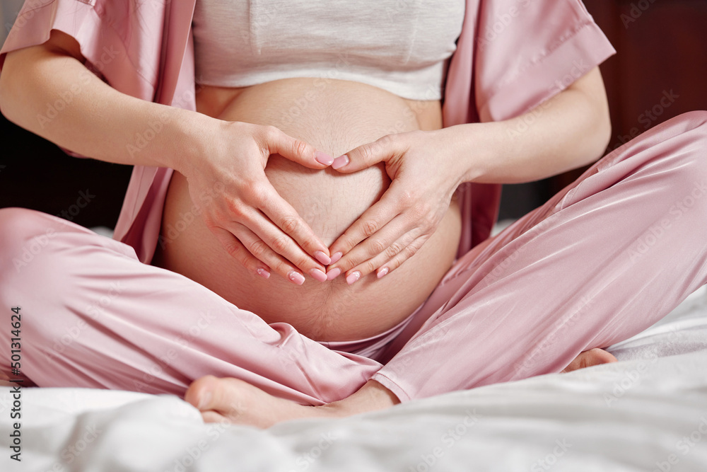 Pregnant woman holding her hands on her belly Pregnant woman holding her hands on her belly