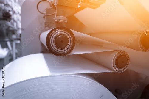Paper alignment unit on the die-cutting machine for the production of self-adhesive labels in the printing house. Paper feeding on the rollers of the machine. Selective focus