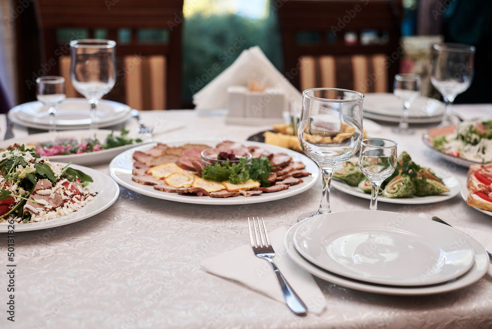 Festive table with delicious appetizers and snacks. Holiday banquet serving with fancy glasses and silverware in restaurant. Wedding birthday party celebration.