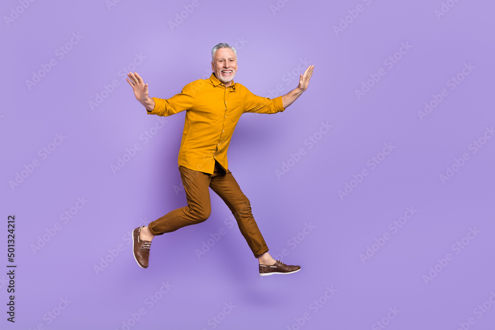 Full size photo of excited mature man have fun jump up energetic isolated over purple color background