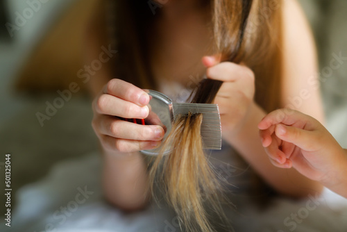 Long-haired European girl child with lice comb, protection. Health and pharmaceutical concept, child health problems. doctor checks child's hair, head lice, possible lice infection.