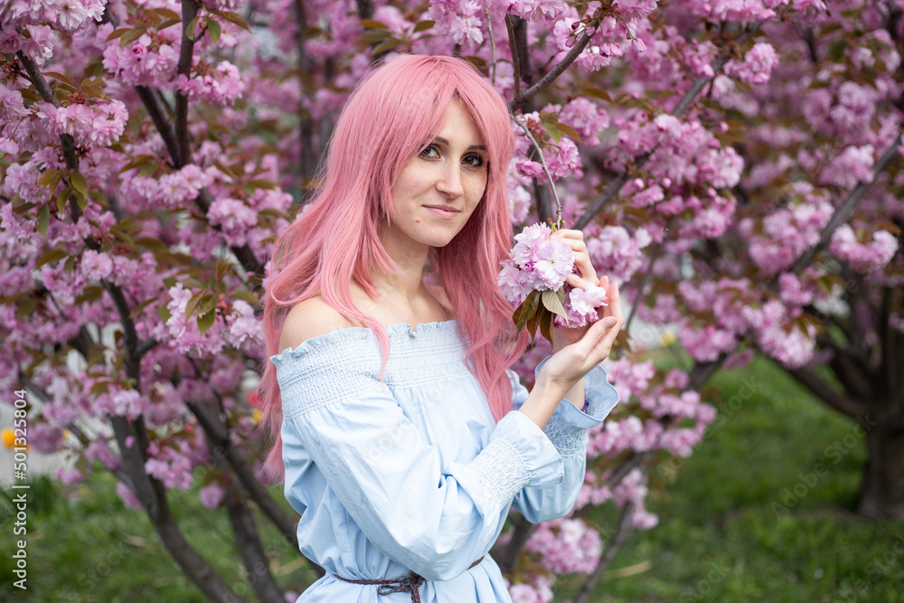 woman in pink wig near sakura blooming tree. Pink flowers, spring and youth concept. Stylish girl smiling. Blooming garden with cherry-tree. Copyplace, place for text. woman in pink wig near sakura blooming tree. Pink flowers, spring and youth concept. Stylish girl smiling. Blooming garden with cherry-tree. Copyplace, place for text.