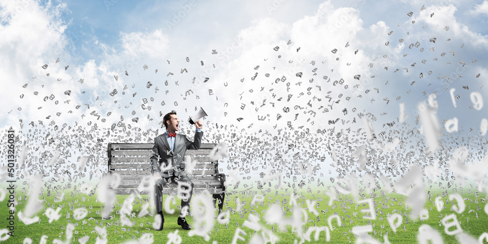 Businessman in summer park announcing something in loudspeaker and symbols fly around Businessman in summer park announcing something in loudspeaker and symbols fly around