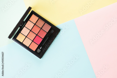 Pallet shadows for applying on face on multicolored background. Eye shadow and eyeliner. Womens beauty.