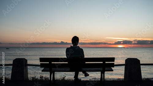 Lonely man watching sunset next to the beach of Agon-Coutainville, France.
