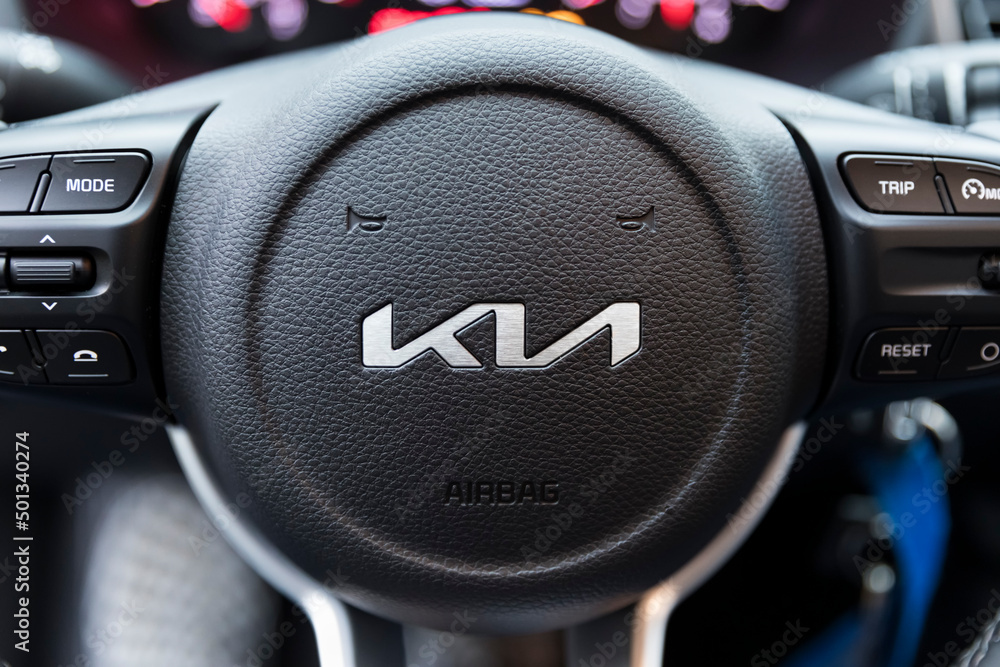 Redesigned KIA brand logo on steering wheel of compact car Stock Photo