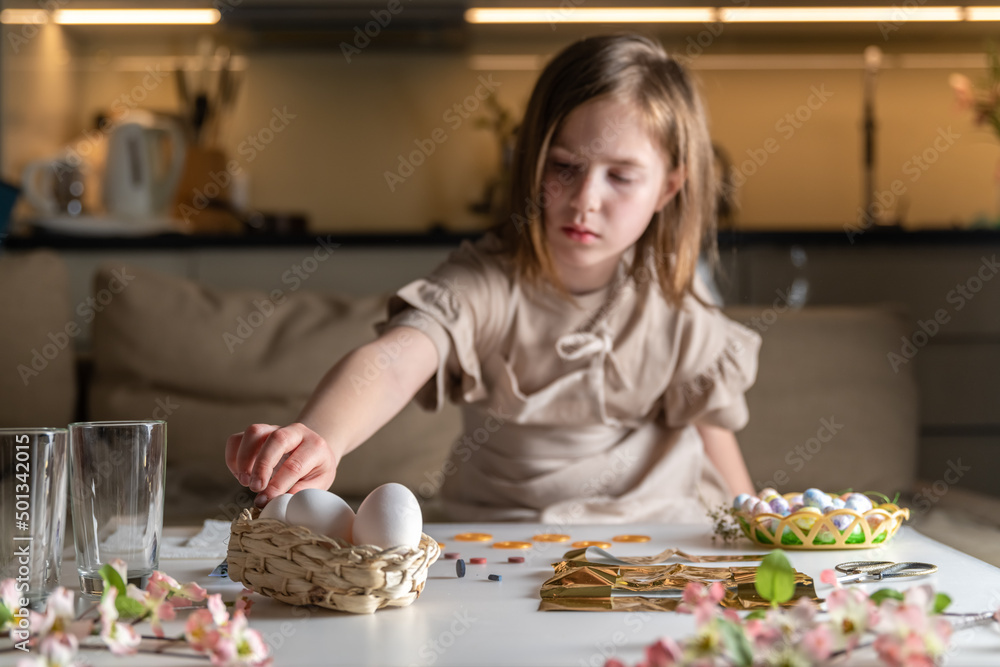 girl at home in the kitchen dyes eggs for Easter