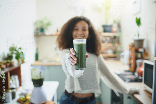 Girl showing her green smoothie at the camera