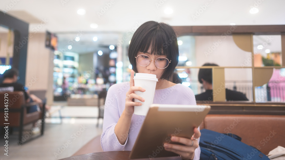 Young adult business asian woman sipping coffee and using tablet for online internet at cafe. Young adult business asian woman sipping coffee and using tablet for online internet at cafe.