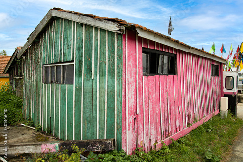 Vieille cabane de pêcheur verte et rose avec un ciel bleu
