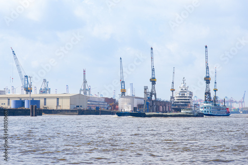 Hamburg cargo port with containers and cranes, in the foreground the river Elbe