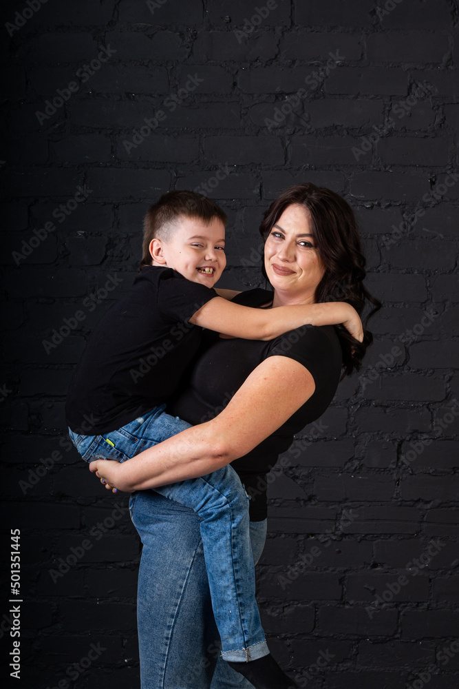 A mother in a black dress holds her son in her arms and sits on a high chair.