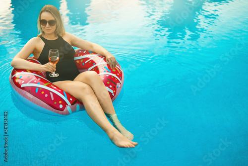 Woman with red glass of wine relaxing in swimming pool. © M-Production