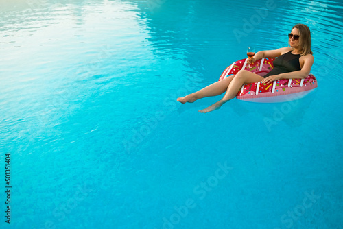 Woman with red glass of wine relaxing in swimming pool. © M-Production