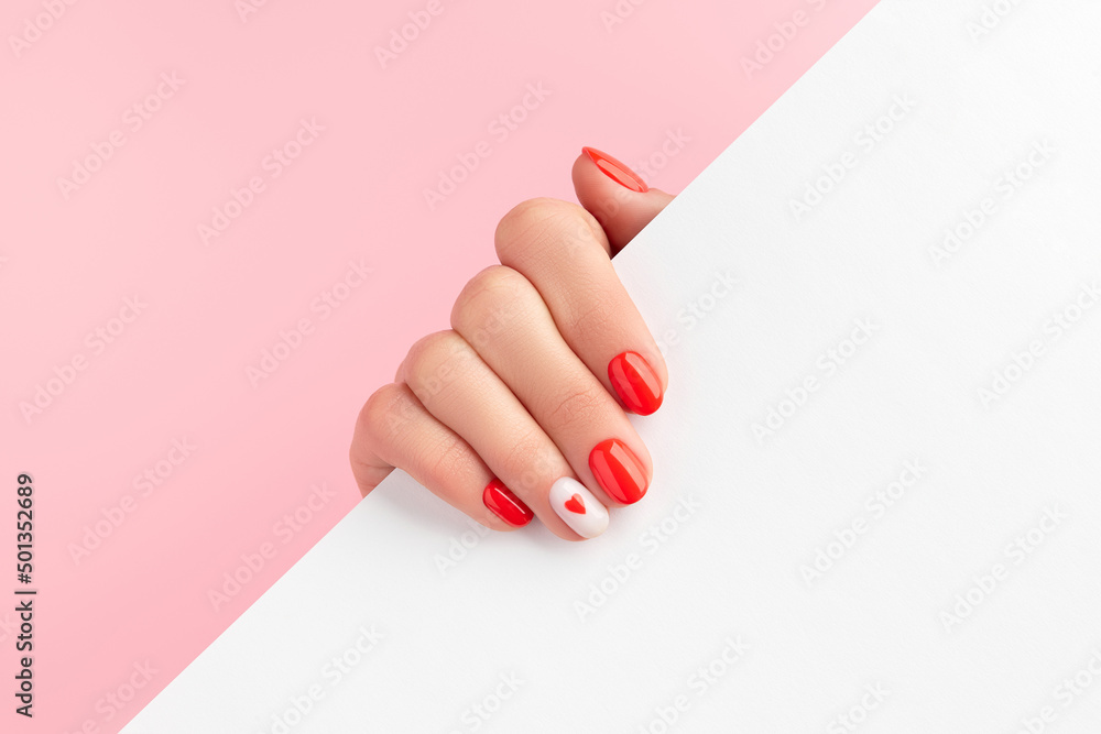 Manicured womans hand holding white paper. Fashionable valentines day nail design - obrazy, fototapety, plakaty 