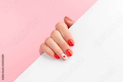 Manicured womans hand holding white paper. Fashionable valentines day nail design photo