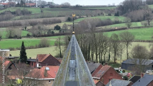 flight upwards to the rooster of the church of westouter in flanders with the fields in the background photo