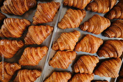 Freshly baked golden French croissants on baking sheet. Fresh classic pastries. Top view . High quality photo