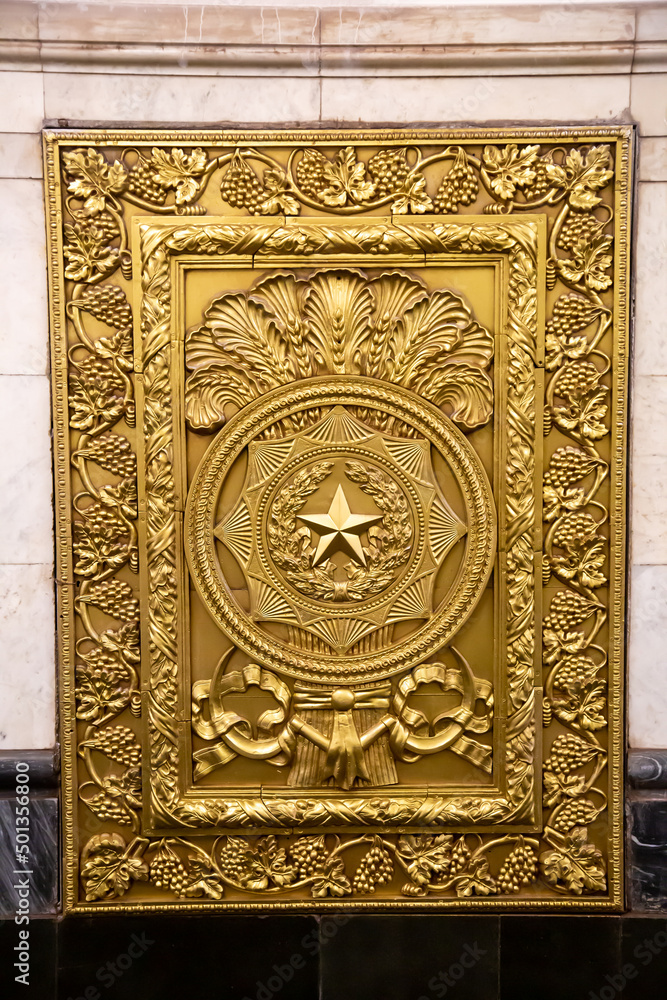 The shield is rectangular in yellow bronze with drawings of grapes around the perimeter, ears and a star in the circle of the center. Architecture is applied art.