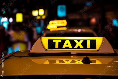 A glowing yellow taxi sign on the roof of a car at night