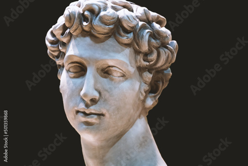 Renaissance sculpture or statue of a male head isolated on black background.