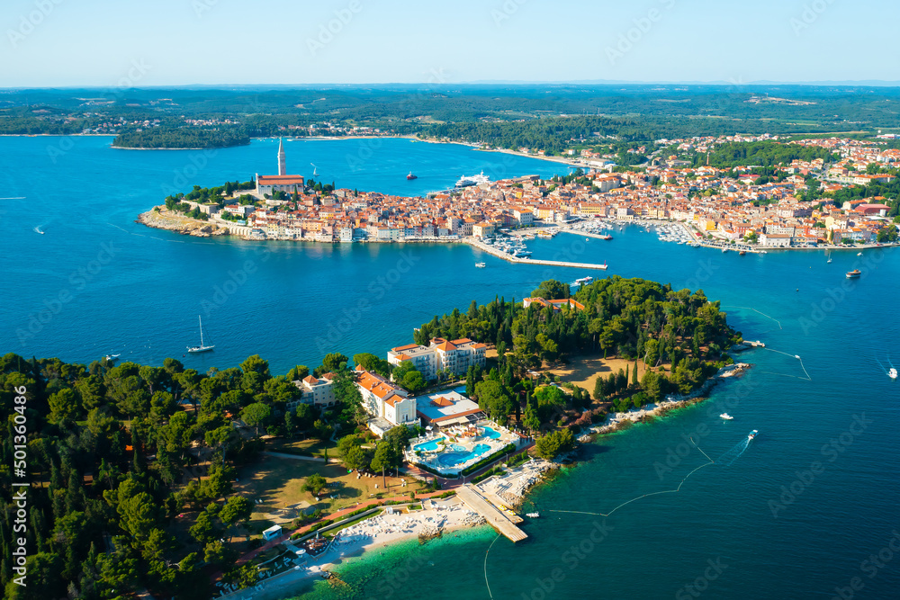 Rovinj surroundings with church of St. Euphemia near Adriatic sea. Villas with swimming pools and buildings with red roofs at bright sunlight. Aerial view
