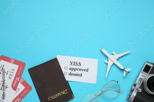 Flat lay composition with passport, toy plane and tickets on light blue background, space for text. Visa receiving