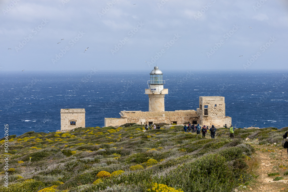 hikers walk towards the Capo Grosso lighthouse on the island of Levanzo. (Egadi) Aegadian Islands, Trapani, Sicily, Italy