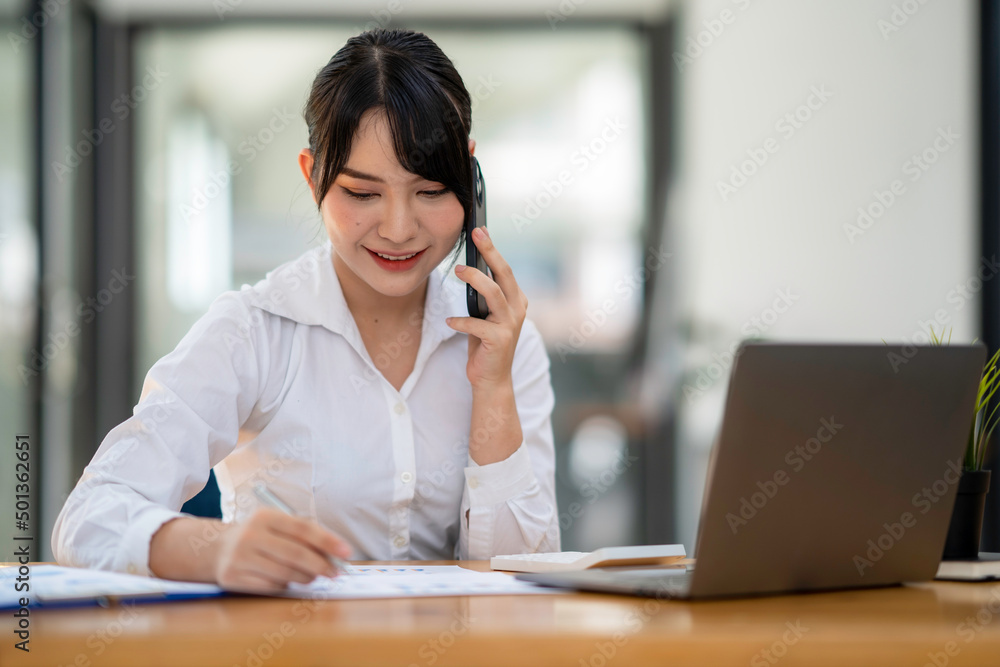business woman using, touching on mobile smart phone screen while working on laptop computer on desk at home office, E-business, internet technology concept business woman using, touching on mobile smart phone screen while working on laptop computer on desk at home office, E-business, internet technology concept