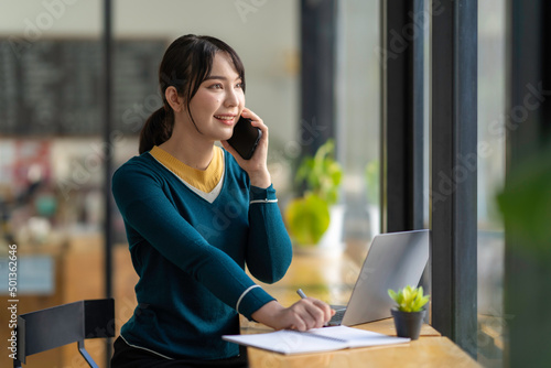 Asian business woman making a phone call and smiling indoor, During break from working in modern office. Mobile business technology concept