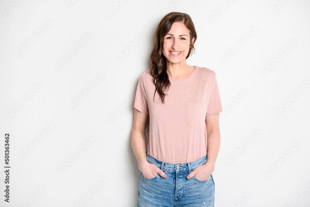 Happy carefree woman with joyful expression, smiling while standing in relaxed pose against white background Happy carefree woman with joyful expression, smiling while standing in relaxed pose against white background