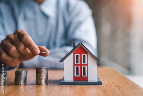 businessman steps coins to find a model house. collecting money to buy a house financial service concept and saving photo