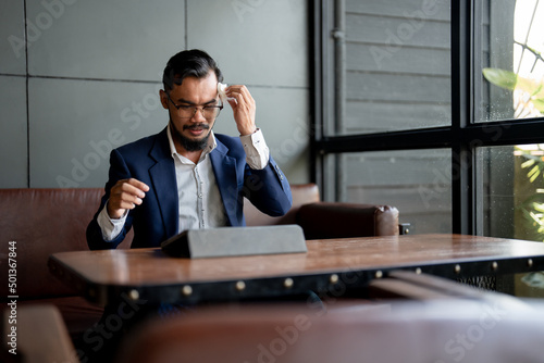 businessman looking at his laptop and is using tissue paper to wipe sweat.