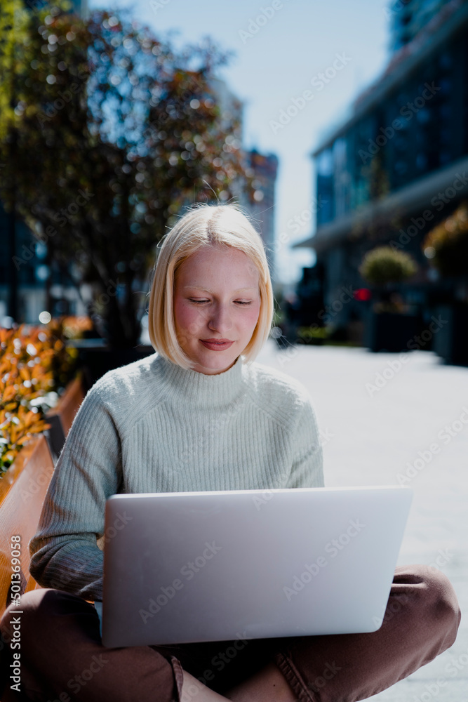 Happy young girl sitting in the park using laptop. Beautiful woman having video call. Happy young girl sitting in the park using laptop. Beautiful woman having video call.