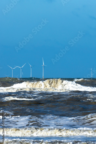 Offshore windmill park in a stormy north sea with spindrift waves photo