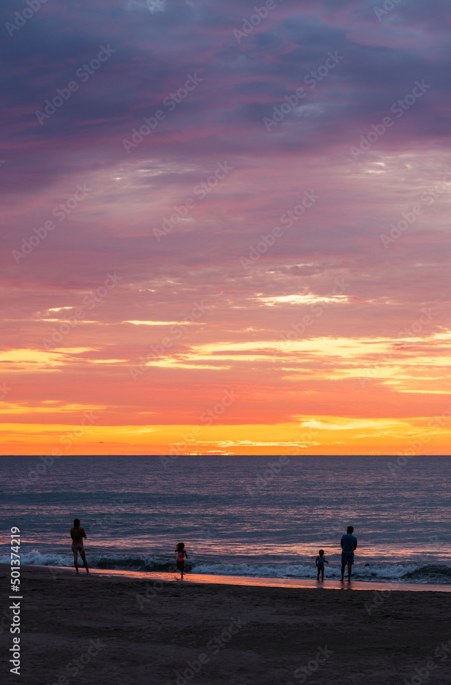 Beach of Same at sunset with people silhouettes and Pacific Ocean sea, Esmeraldas province, Ecuador.