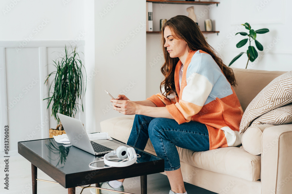 Concentrated young business woman working at home with mobile phone and laptop. Concentrated young business woman working at home with mobile phone and laptop.