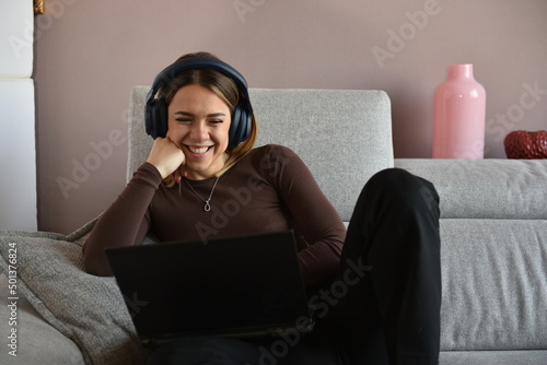 bellissima ragazza sorridente che guarda il monitor del computer seduta sul divano photo