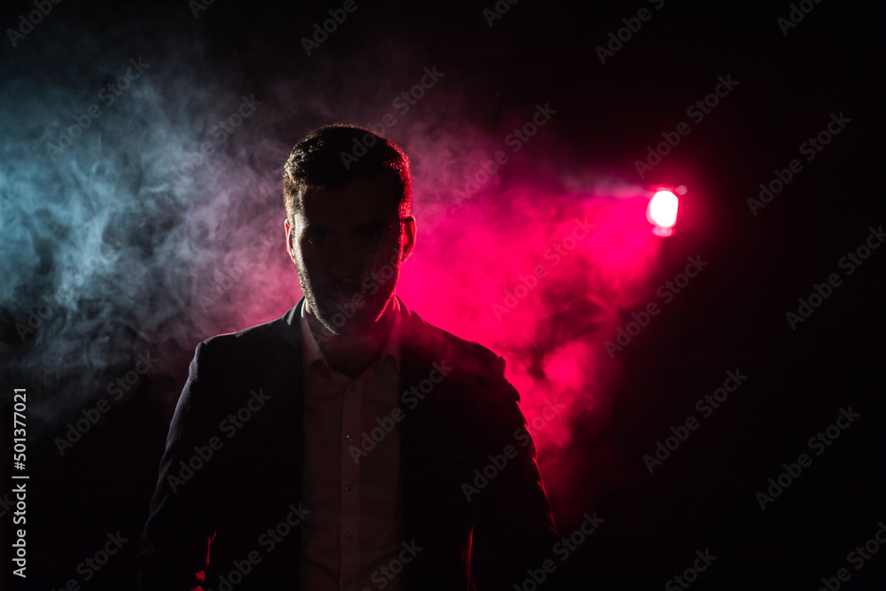 Photo of standing man and pink light on the background.