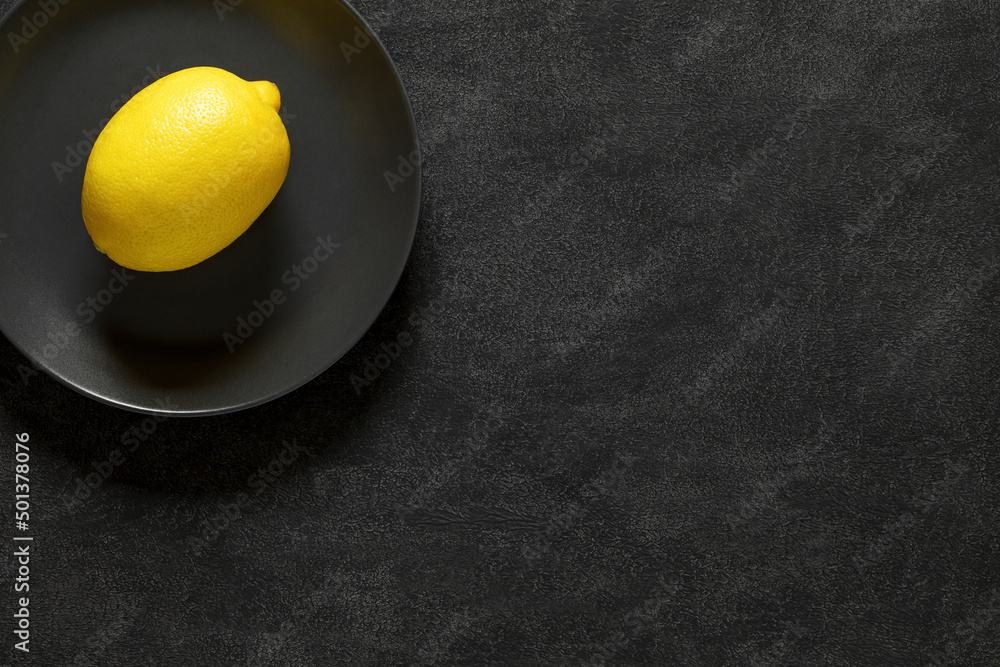 Lemon whole in gray plate, on dark background, top view, space to copy text. Lemon whole in gray plate, on dark background, top view, space to copy text.