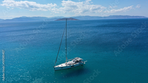 Aerial drone photo of beautiful sail boat anchored in Aegean island paradise bay with turquoise sea