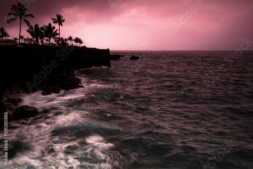 Silhouette view of cliffs, rocks and plants at Kona Coast against red dusk sky in Kaua'i Island, USA photo