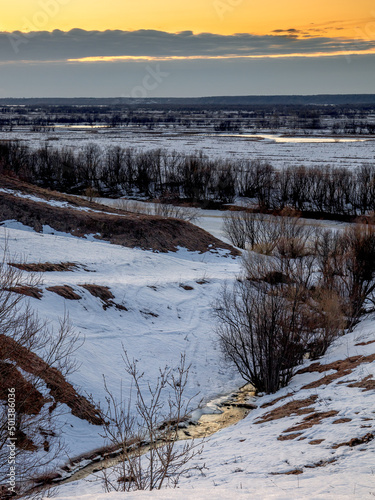Evening view of the ravine with a stream from melted snow at sunset. The coming of spring