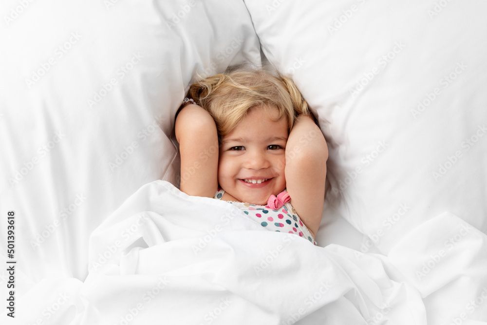 Happy toddler snuggling on white bed Happy toddler snuggling on white bed