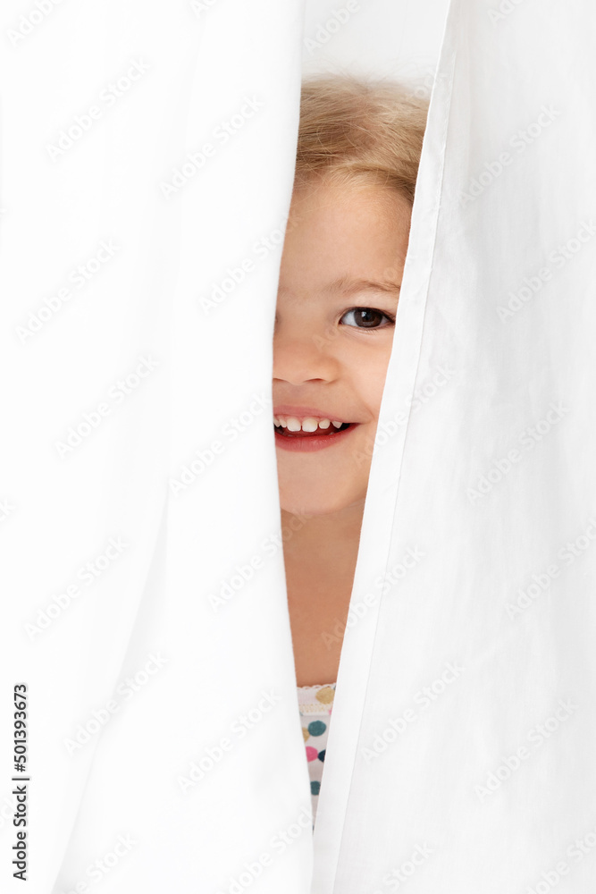 Smiling face of happy young girl peeking behind white sheet Smiling face of happy young girl peeking behind white sheet