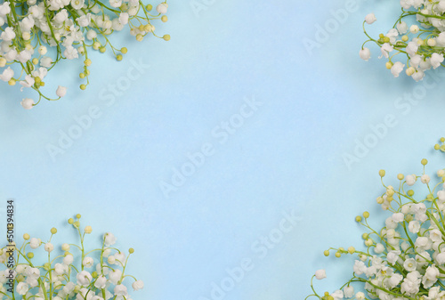 White flowers Lily of the valley ( Convallaria majalis, May bells, may lily ) on a blue paper background with space for text. Top view, flat lay © Anastasiia Malinich